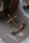 Bronze anchor pendant on a textured surface with star anise in the background